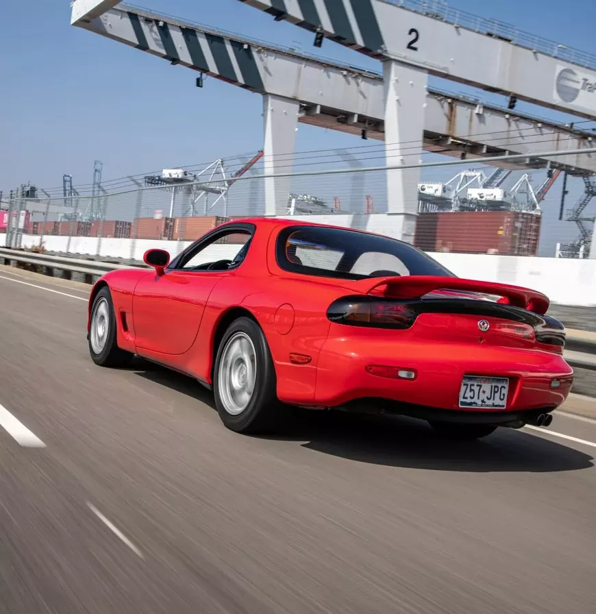 A red 1995 Mazda RX7 FD shot by Stance Auto Magazine Photographers driving up the road