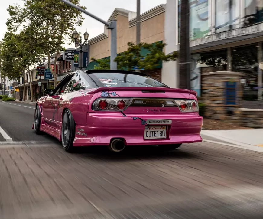 A pink 1989 Nissan 240SX speeding down the road