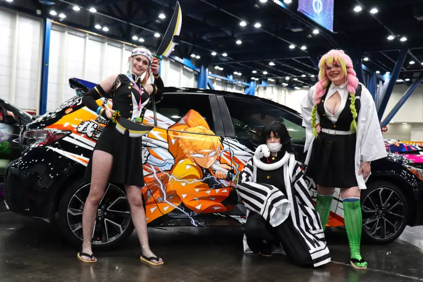 3 Girls dressed in cosplay at the side of a car