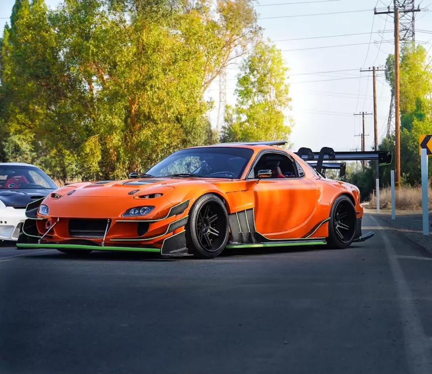 An RX7 FD in orange with a Rocket Bunny kit