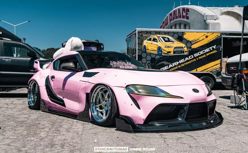 A pink Toyota Supra MK5 on display at a car show in the USA carnvl