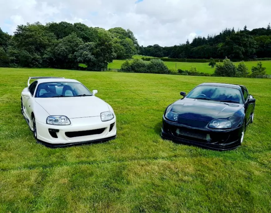 A white and a Black Toyota Supra parked in a field